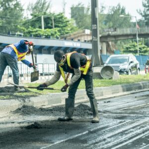 man in blue and yellow jacket and black pants walking on road during daytime