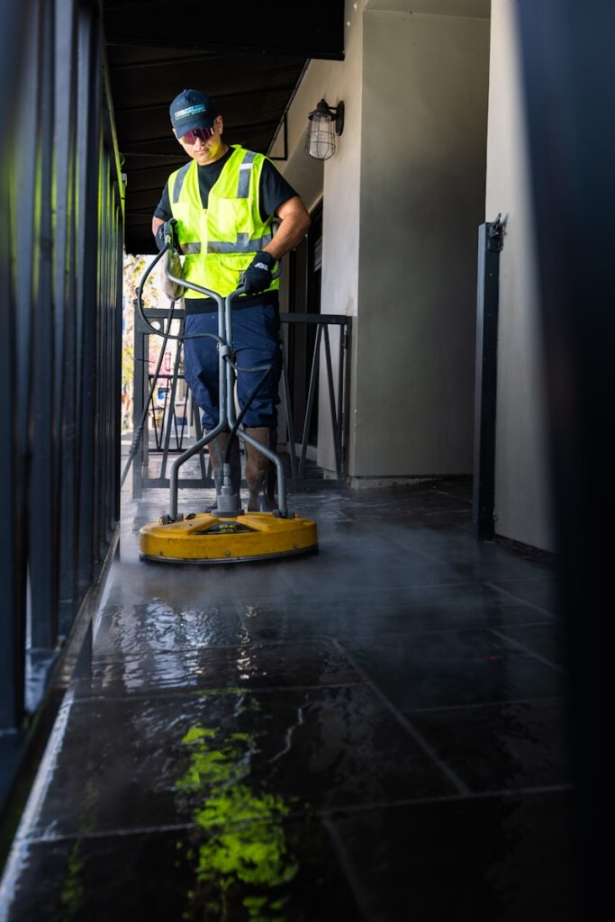 a man in a yellow vest is cleaning the floor